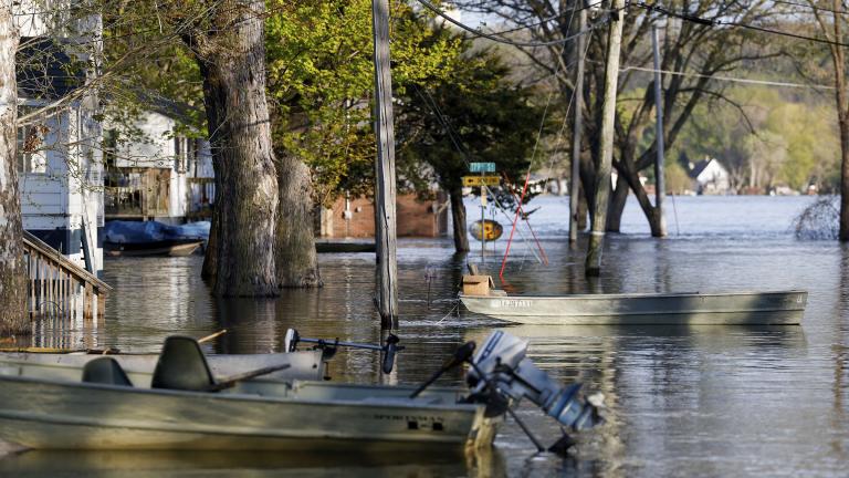 Boats float tethered in the front yards of homes along South Spencer Road as the Mississippi River continues to rise forcing residents to make alternative transportation between their homes and the rising water covering their street, Thursday, April 27, 2023, in Pleasant Valley, Iowa. (Nikos Frazier / Quad City Times via AP)