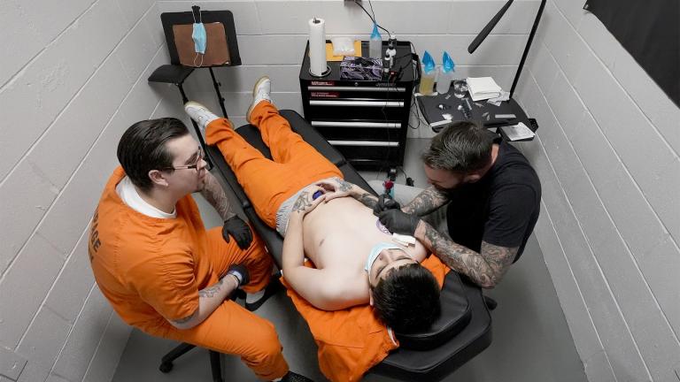 Brett, left, a detainee at the DuPage County Jail, watches and learns as tattoo artist Tom Begley works on a tattoo for Jaime Marinez to cover a bullet hole scar that depicts the date and time of Marinez's father's death, Thursday, Feb. 3, 2022, in Wheaton, Ill. (AP Photo / Charles Rex Arbogast)