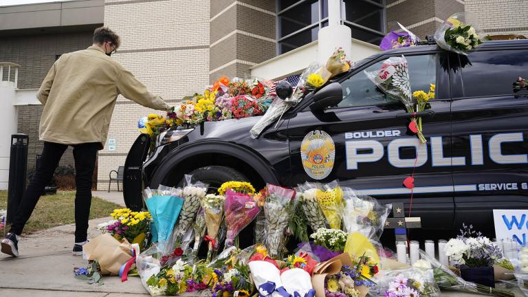 A man leaves a bouquet on a police cruiser parked outside the Boulder Police Department after an officer was one of the victims of a mass shooting at a King Soopers grocery store Tuesday, March 23, 2021, in Boulder, Colo. (AP Photo / David Zalubowski)