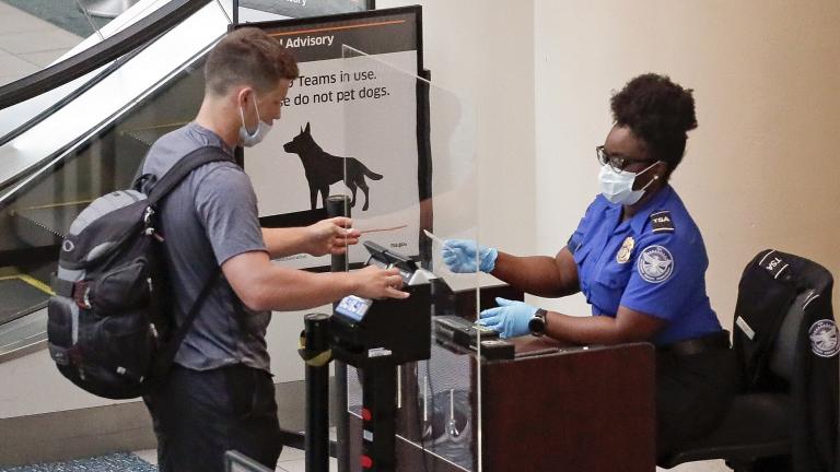In this June 17, 2020 file photo, a TSA worker, right, checks a passenger before entering a security screening at Orlando International Airport in Orlando, Fla..  (AP Photo / John Raoux, File)