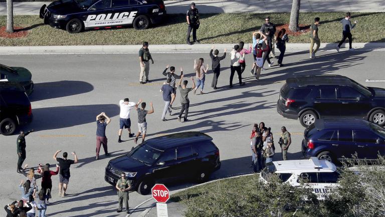 Students hold their hands in the air as they are evacuated by police from Marjory Stoneman Douglas High School in Parkland, Fla., on Feb. 14, 2018, after a shooter opened fire on the campus. (Mike Stocker / South Florida Sun-Sentinel via AP, File)