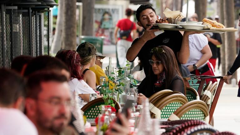 A waiter delivers food to patrons at a restaurant, Jan. 21, 2022, in Miami Beach, Fla. (AP Photo/Marta Lavandier, File)