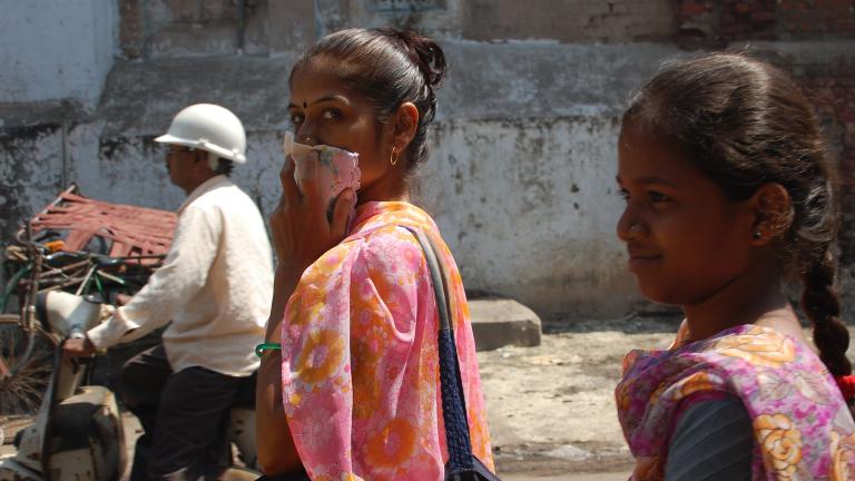 A woman covers her mouth with a handkerchief while walking through the streets of Ahmedabad, India. (Jill Ryan / WBUR Boston’s NPR News Station / Flickr)