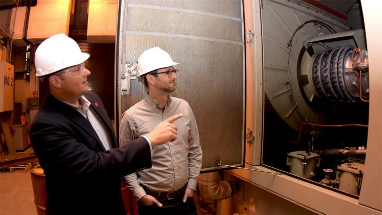 Cliff Haefke, director of the UIC Energy Resources Center, left, and policy analyst Graeme Miller analyze the 7-megawatt combined heat and power combustion turbine at the UIC West Campus Utilities Plant. (Courtesy University of Illinois at Chicago)