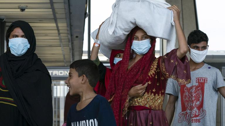 People evacuated from Kabul, Afghanistan, walk through the terminal before boarding a bus after they arrived at Washington Dulles International Airport, in Chantilly, Va., on Monday, Aug. 30, 2021. (AP Photo / Jose Luis Magana)