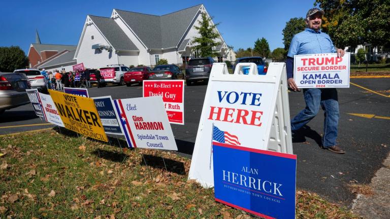 A supporter for former President Trump walks past political signs outside the Rutherford County Annex Building, an early voting site, Thursday, Oct. 17, 2024 in Rutherfordton, N.C. (AP Photo / Kathy Kmonicek)