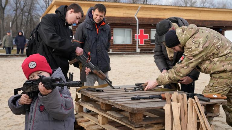 A boy plays with a weapon while an instructor shows a Kalashnikov assault rifle during a training of members of a Ukrainian far-right group train, in Kyiv, Ukraine, Sunday, Feb. 20, 2022. (AP Photo / Efrem Lukatsky)