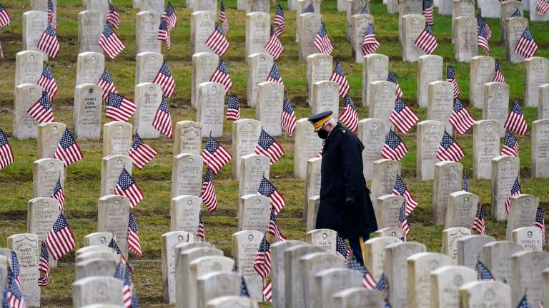 Retired U.S. Army veteran Bill MacCully walks among flag-covered graves in the Veterans Cemetery of Evergreen Washelli Memorial Park on Veterans Day, Wednesday, Nov. 11, 2020, in Seattle. (AP Photo / Elaine Thompson)