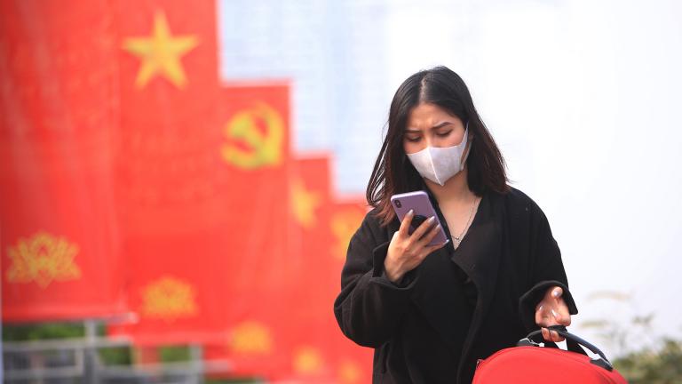 In this Jan. 23, 2021 file photo, a woman wearing face mask looks at her phone in Hanoi, Vietnam. (AP Photo / Hau Dinh, File)
