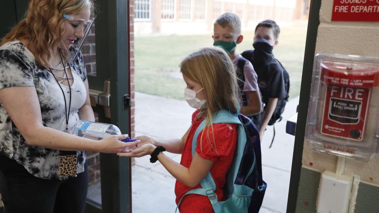 In this Aug. 5, 2020, file photo, wearing masks to prevent the spread of COVID19, elementary school students use hand sanitizer before entering school for classes in Godley, Texas. (AP Photo/LM Otero, File)