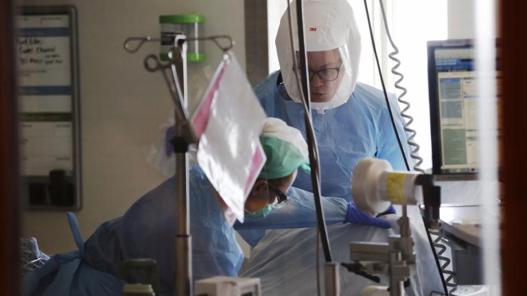 In this May 8, 2020, file photo registered nurses Beth Andrews, top, and Erin Beauchemin work with a patient in the COVID-19 Intensive Care Unit at Harborview Medical Center in Seattle. (AP Photo / Elaine Thompson, File)