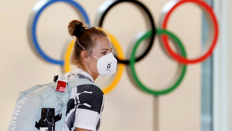 A German athlete, wearing face mask, walks past the Olympic rings display on their arrival at Haneda airport in Tokyo, Thursday, July 1, 2021. (Kyodo News via AP)