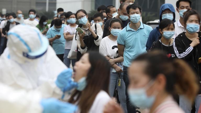 In this Friday, May 15, 2020 file photo, people line up for coronavirus testing at a large factory in Wuhan in central China's Hubei province. In June 2020, China reported using batch testing as part of a recent campaign to test all 11 million residents of Wuhan, the city where the virus first emerged late in late 2019. (Chinatopix Via AP)
