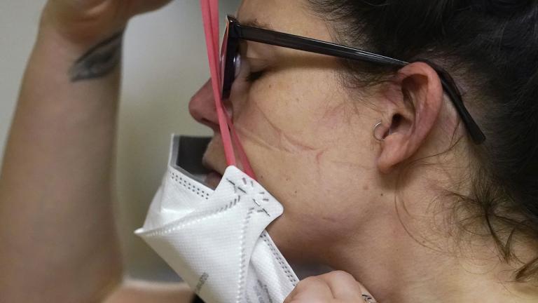 Registered nurse Jessalynn Dest pulls on a new N95 mask as indentations remain from another she had just removed after leaving a COVID-19 patient room in the acute care unit of Harborview Medical Center, Jan. 14, 2022, in Seattle. (AP Photo / Elaine Thompson, File)