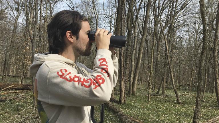 In this March 24, 2020 photo, provided by Conner Brown, he is seen using binoculars to look for birds in Cedar Island, Maryland. (Elizabeth Wright / Courtesy of Conner Brown via AP)