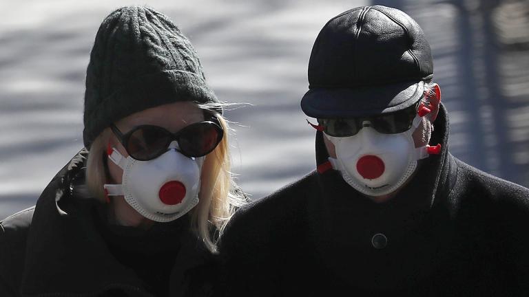 Two people wearing masks walk in Regents Park in London, Monday, March 23, 2020. (AP Photo / Frank Augstein, File)