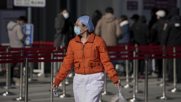 A nurse wearing a face mask to help curb the spread of the coronavirus walks by people lining up for a coronavirus test at a hospital in Beijing, Sunday, Jan. 17, 2021. (AP Photo / Andy Wong)