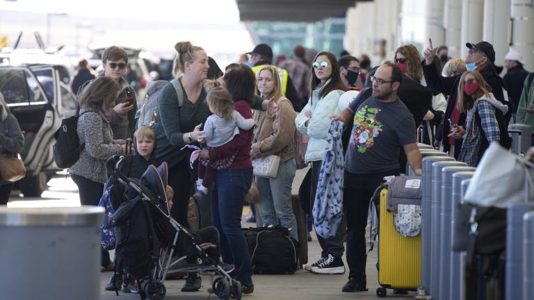Travelers queue up at the Southwest Airlines curbside check-in area at Denver International Airport Sunday, Dec. 26, 2021, in Denver. Airlines canceled hundreds of flights Sunday, citing staffing problems tied to COVID-19 to extend the nation's travel problems beyond Christmas. (AP Photo/David Zalubowski)
