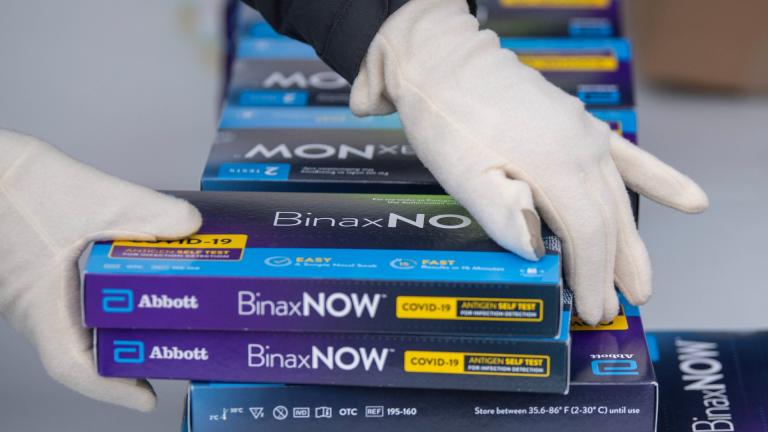 Youngstown City Health Department worker Faith Terreri grabs two at-home COVID-19 test kits to be handed out during a distribution event, Dec. 30, 2021, in Youngstown, Ohio. (AP Photo / David Dermer, File)