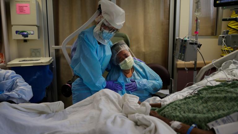 In this July 31, 2020, file photo, Romelia Navarro, right, is comforted by nurse Michele Younkin as she weeps while sitting at the bedside of her dying husband, Antonio, in St. Jude Medical Center's COVID-19 unit in Fullerton, Calif. (AP Photo / Jae C. Hong, File)