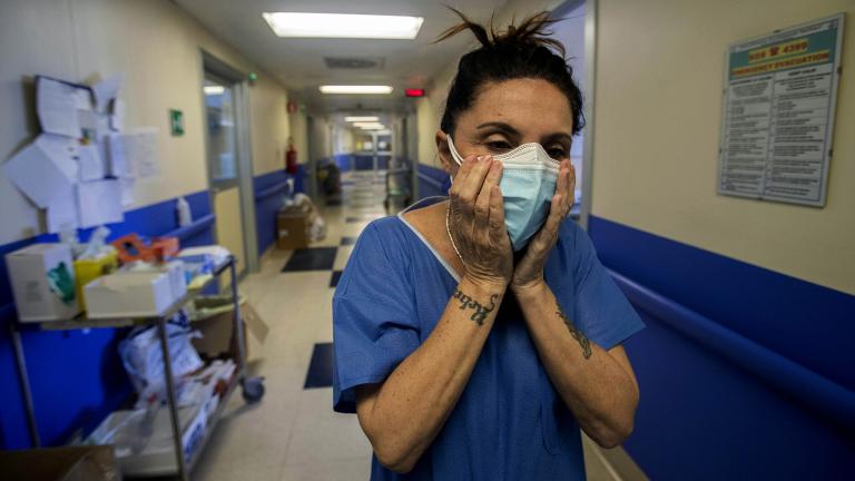 In this April 10, 2020, file photo, nurse Cristina Settembrese fixes two masks to her face during her work shift in the COVID-19 ward at the San Paolo hospital in Milan, Italy. (AP Photo / Luca Bruno, File)