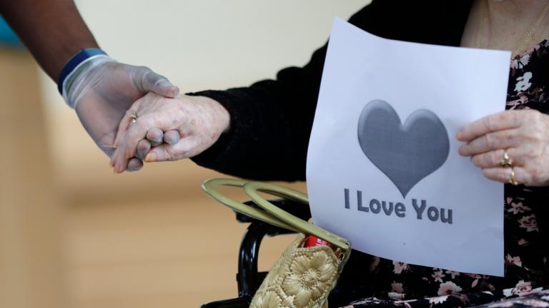 In this July 17, 2020 file photo, a senior citizen holds the hand of a care coordinator at a Health facility in Miami. (AP Photo / Wilfredo Lee)