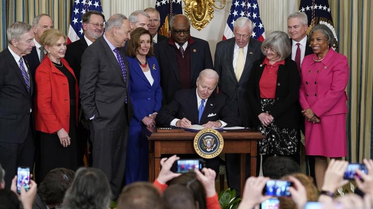 President Joe Biden signs the Postal Service Reform Act of 2022 in the State Dining Room at the White House in Washington, April 6, 2022. Watching from left are Rep. Stephen Lynch, D-Mass., Sen. Tom Carper, D-Del., Rep. Carolyn Maloney, D-N.Y., Sen. Gary Peters, D-Mich., Senate Majority Leader Chuck Schumer of N.Y., Sen. Rob Portman, R-Ohio, House Speaker Nancy Pelosi of Calif., Rep. James Clyburn, D-S.C., Rep. Steny Hoyer, D-Md., Annette Taylor, Rep. James Comer, R-Ky., and Rep. Brenda Lawrence, D-Mich. (A