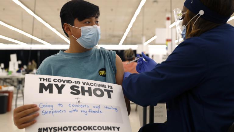 Lucas Kittikamron-Mora, 13, holds a sign in support of COVID-19 vaccinations as he receives his first Pfizer vaccination at the Cook County Public Health Department, May 13, 2021 in Des Plaines, Ill. (AP Photo/Shafkat Anowar, file)