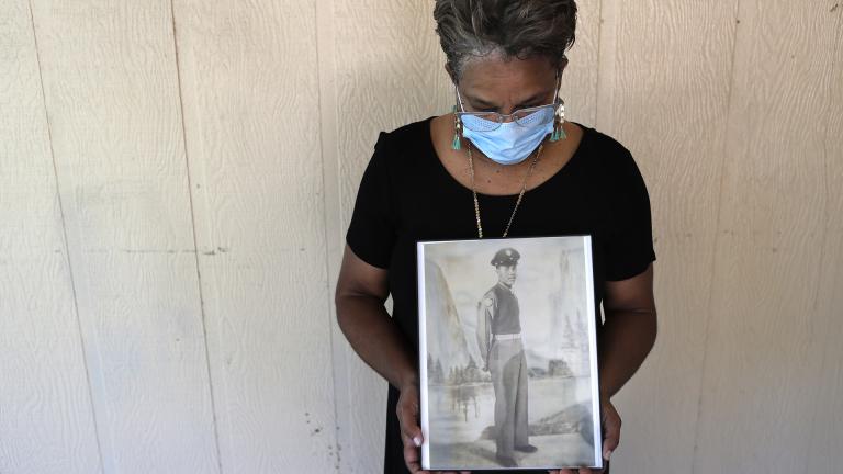 In this May 18, 2020, file photo, Belvin Jefferson White poses with a portrait of her father Saymon Jefferson at Saymon’s home in Baton Rouge, La. Belvin recently lost both her father and her uncle, Willie Lee Jefferson, to COVID-19.  (AP Photo/  Gerald Herbert, File)