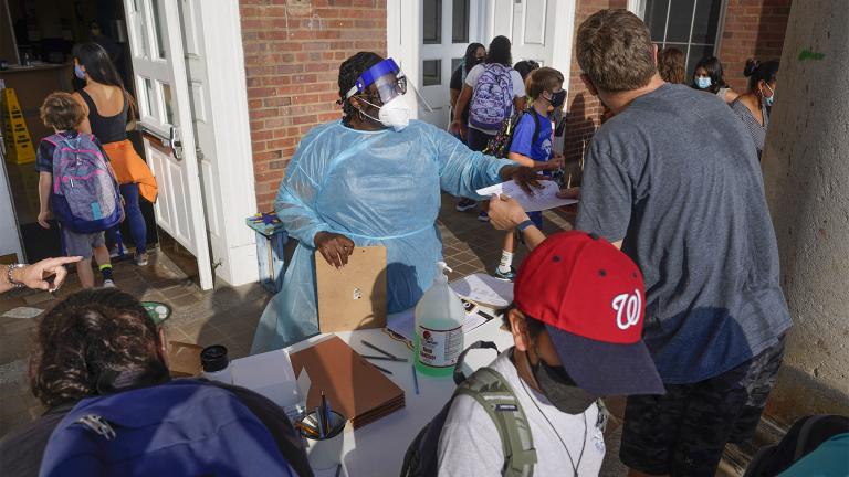 A Healthcare worker directs parents and students arriving at the main entrance of the Adams campus of Oyster-Adams Adams bilingual school, in Washington, Aug. 30, 2021. (AP Photo / Pablo Martinez Monsivais, File)
