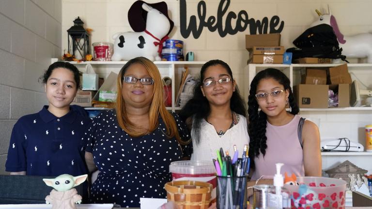 Aja Purnell-Mitchell, second from left, sits with her three children, Cartier, 14, left; Kyra, 15, and Kyla, 13, at a local food hub in Durham, N.C., on Friday, May 28, 2021, where they often help their mother. (AP Photo/Gerry Broome)
