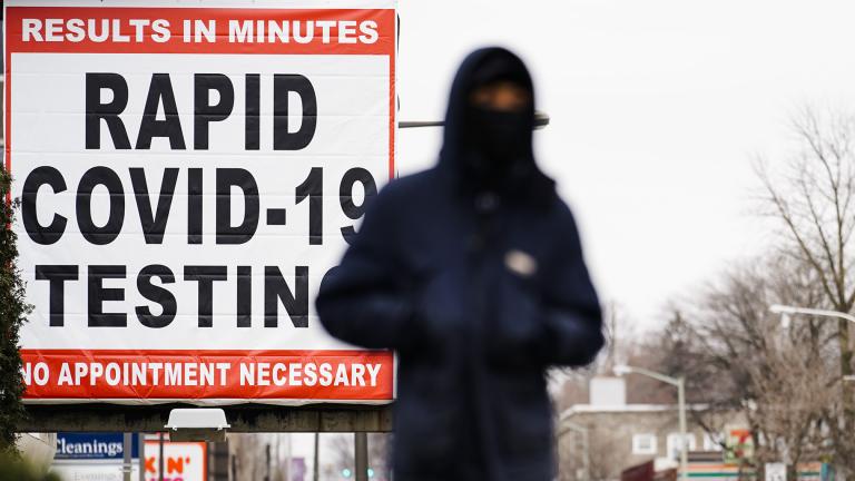 In this Jan. 25, 2021, file photo, a person wearing face mask as a precaution against the coronavirus walks near a sign advertising a rapid COVID-19 testing site in Philadelphia. (AP Photo / Matt Rourke, File)