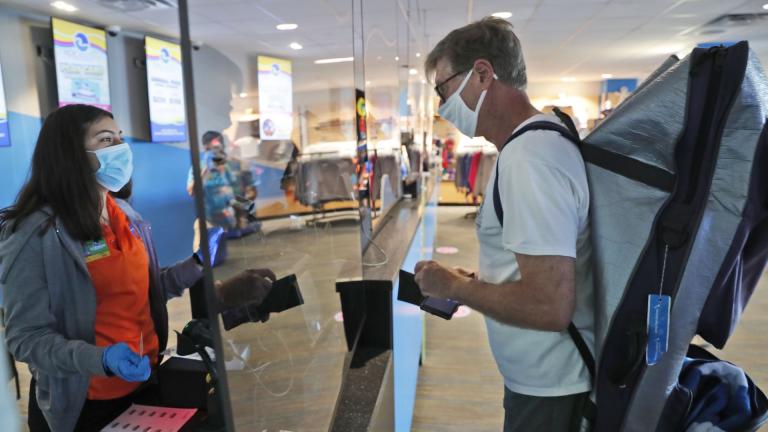 Amid concerns of the spread of COVID-19, a cashier and customer are separated by plexiglass at the city owned waterpark in Grand Prairie, Texas, Friday, May 29, 2020. Water parks in Texas were allowed to reopen today. (AP Photo/LM Otero)