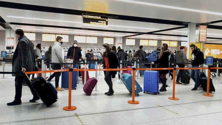 In this Dec. 20, 2020, file photo, passengers queue for check-in at Gatwick Airport in West Sussex, England, south of London. (Gareth Fuller / PA via AP)