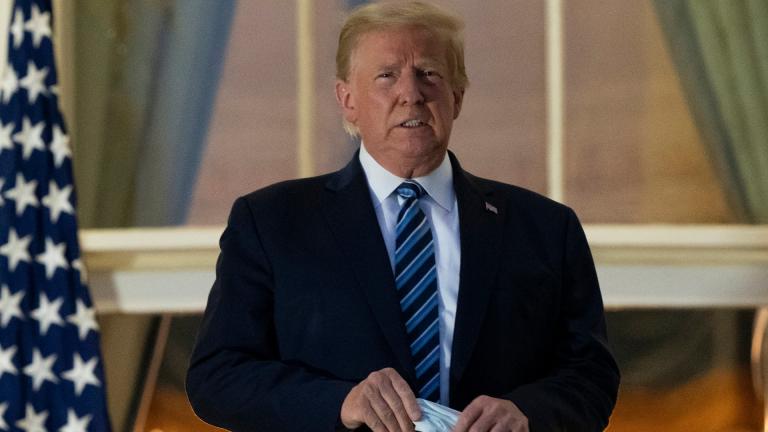  In this Monday, Oct. 5, 2020 file photo, President Donald Trump holds his mask after removing it from his face as he stands on the Blue Room Balcony upon returning to the White House in Washington from the Walter Reed National Military Medical Center in Bethesda, Md. He announced he tested positive for the coronavirus on Oct. 2. (AP Photo/Alex Brandon)