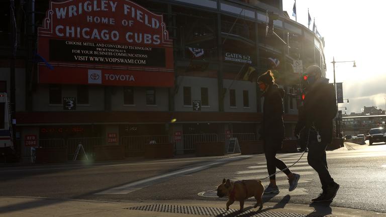 People walk their dog outside of Wrigley Field on opening day for the Chicago Cubs, Thursday, April 1, 2021, in Chicago. (AP Photo / Shafkat Anowar)