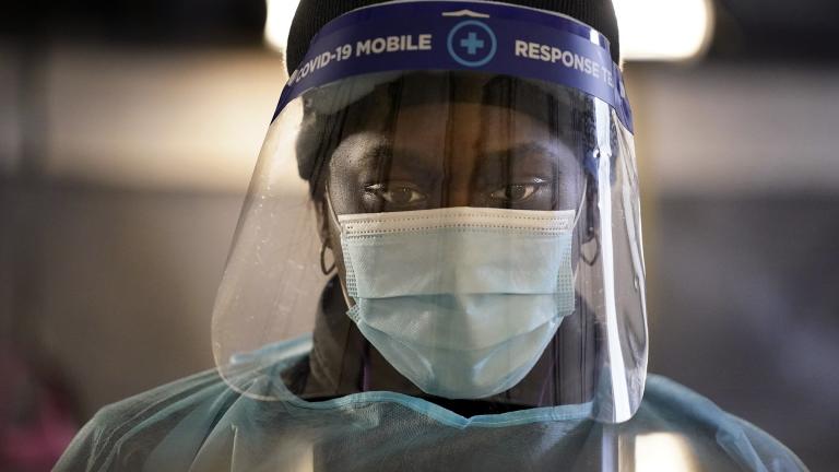 In this Dec. 8, 2020, file photo, a health care worker wears personal protective equipment as she speaks to a patient at a mobile testing location for COVID-19 in Auburn, Maine. (AP Photo / Robert F. Bukaty, File)