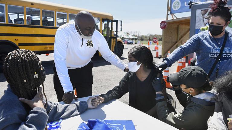 In this April 26, 2021, file photo, East Hartford High School senior Sudeen Pryce, right, center, receives support from classmate Alexia Phipps, left, East Hartford High School Intervention Coordinator Mark Brown, second from left, and EMT Katrinna Greene, top right, of Manchester, as RN Kaylee Cruz of Bristol administers the first dose of the Pfizer vaccine to Pryce at a mass vaccination site at Pratt & Whitney Runway in East Hartford, Conn. (AP Photo / Jessica Hill, File)