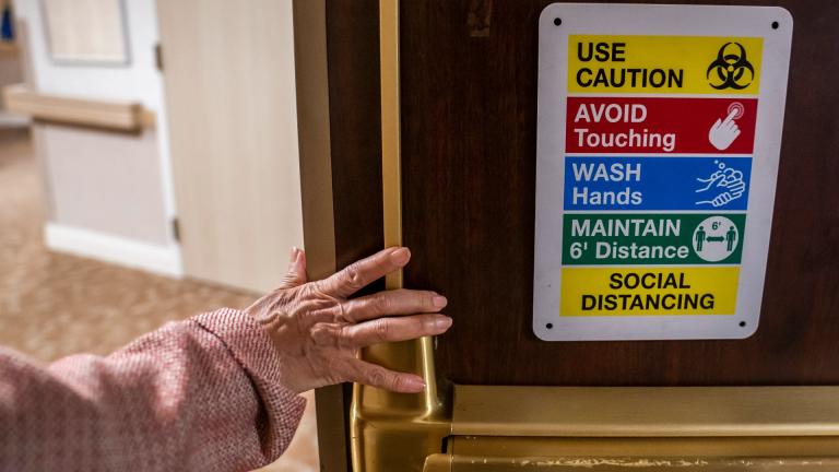 Tina Sandri, CEO of Forest Hills of DC senior living facility, passes a COVID-19 informational sign while walking to her office on Thursday, Dec. 8, 2022, in Washington. Coronavirus-related hospital admissions are climbing again in the United States, with older adults a growing share of U.S. deaths. (AP Photo / Nathan Howard)