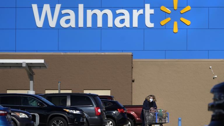  A woman wheels a cart with her purchases out of a Walmart store, Nov. 18, 2020, in Derry, N.H. (AP Photo/Charles Krupa, File)