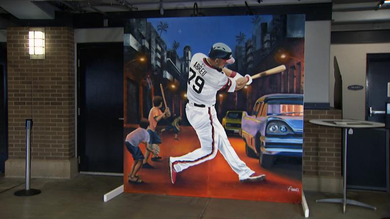 In a mural by Chicago artist Asend, a larger-than-life Jose Abreu swings his mighty bat under the Cienfuegos streetlights of his childhood. (WTTW News)