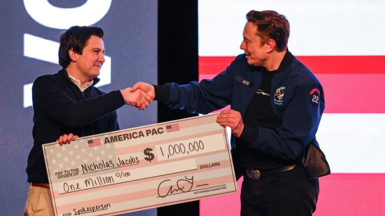Elon Musk presents a check for $1 million dollars to a man during a town hall Sunday, March 30, 2025, in Green Bay, Wis. (AP Photo / Jeffrey Phelps)