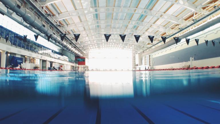 A pool with empty lanes and pennants overhead. (Artem Verbo / Unsplash)