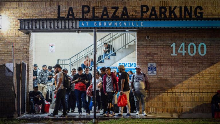 Migrants stand at a processing center as they wait for a bus to Chicago, in downtown Brownsville, Texas, on Oct. 24, 2023. (Carlos Barria / Reuters)