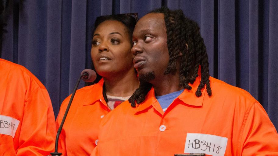 Antonio Lightfoot, deputy director at the nonprofit Workers Center for Racial Justice, speaks at a news conference in the Illinois State Capitol. Advocates wore orange jumpsuits to symbolize the restrictions placed on people who return to society from prison. (Dilpreet Raju / Capitol News Illinois)