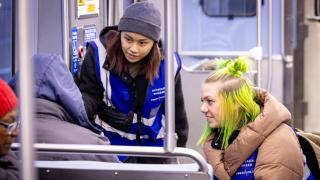 Caseworkers MG Hibionada and Ell Fabricius talk to a person on the Red Line about shelter options. Fabricius and Hibionada are members of the Thresholds team on the CTA, which provides outreach and services to people sheltering on the trains. (Kathleen Hinkel / Block Club Chicago)