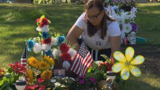 Lourdes Lara tends to the grave of her son, Chrys Carvajal, who was shot and killed in July 2021. (WTTW News)