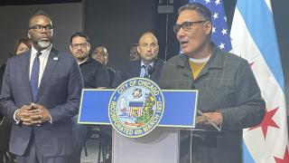 Mayor Brandon Johnson looks on as Grace and Peace Church Pastor John Zayas speaks about efforts to help shelter the 1,250 migrants sleeping at Chicago police stations and at O’Hare International Airport on Nov. 28, 2023. (Heather Cherone / WTTW News)