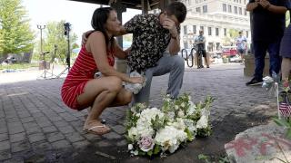 Brooke and Matt Strauss, who were married Sunday, pause after leaving their wedding bouquets in downtown Highland Park, Ill., a Chicago suburb, near the scene of Monday's mass shooting, Tuesday, July 5, 2022. (AP Photo / Charles Rex Arbogast)