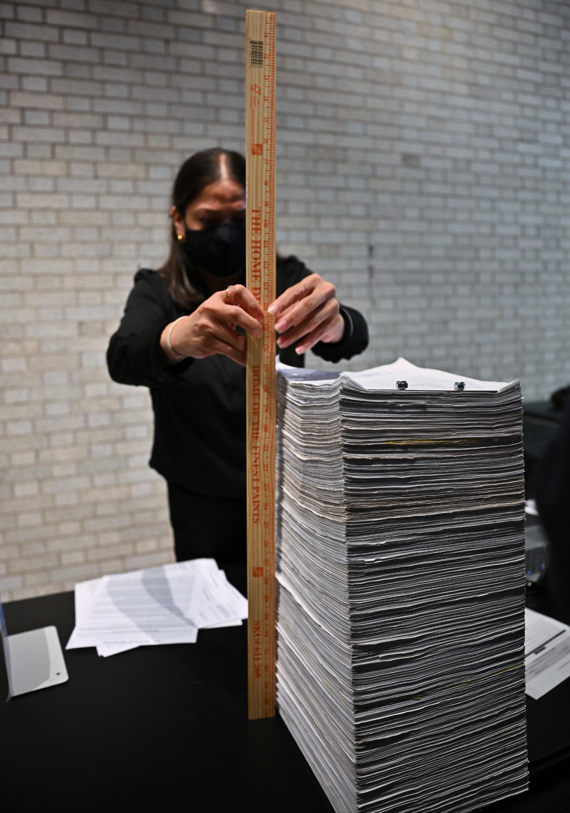A Chicago Board of Election Commissioners employee measures a stack of petitions on the first day of candidate filing on Oct. 19, 2026. (Victor Hilitski / WTTW News)